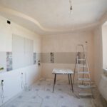 Spacious kitchen under renovation with ladder and tools, showcasing a fresh new design.