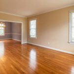 Bright empty room with wooden floors and large windows, ideal for real estate listings.